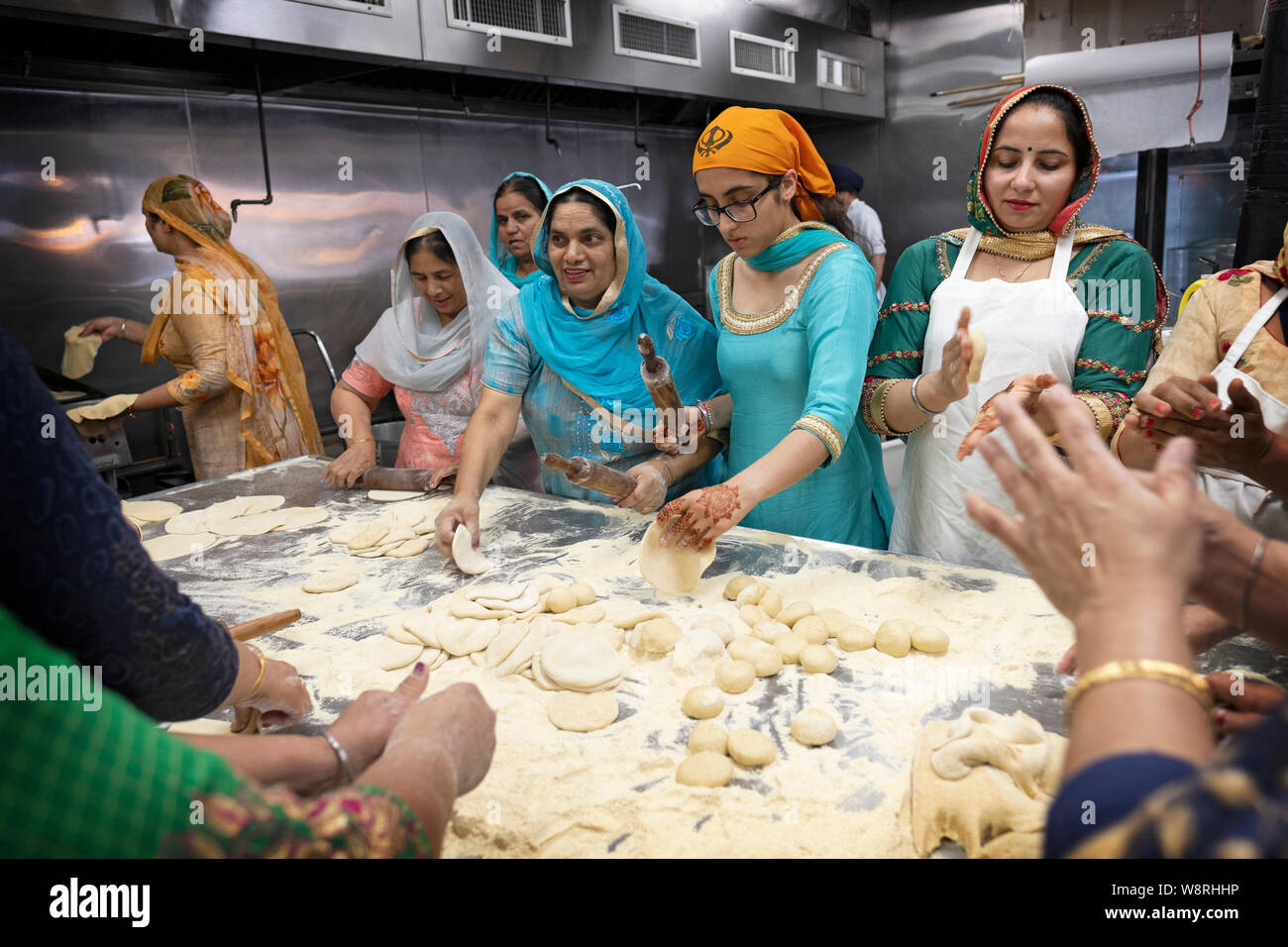 I volontari di varie età preparare roti pane a langar in un tempio sikh in Sud Ozone Park, Queens, a New York City. Foto Stock