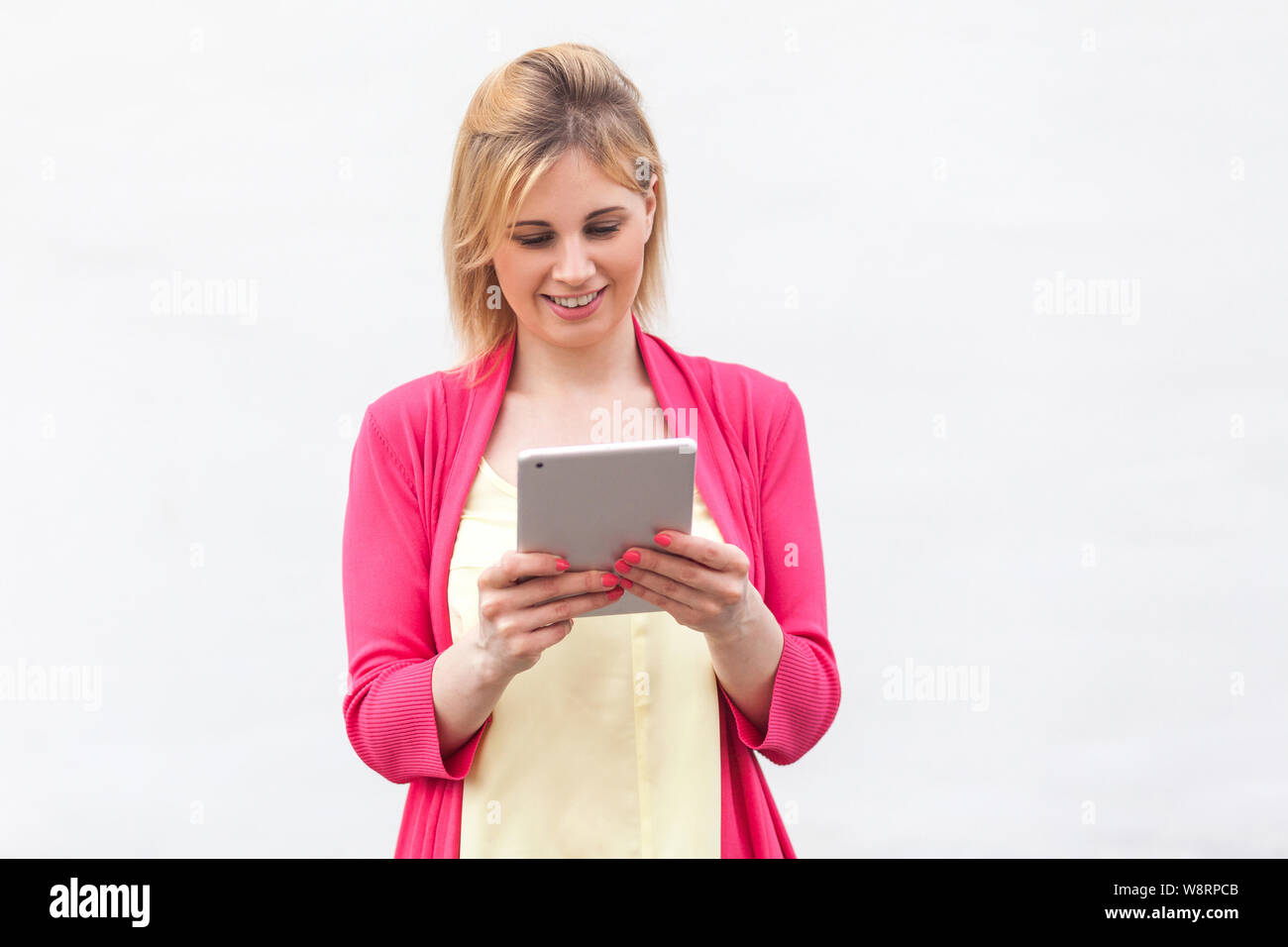 Ritratto di bella Imprenditrice di successo giovane donna in rosa camicetta in piedi, di utilizzo e di lettura del messaggio di interessanti sul suo tablet con felice fac Foto Stock