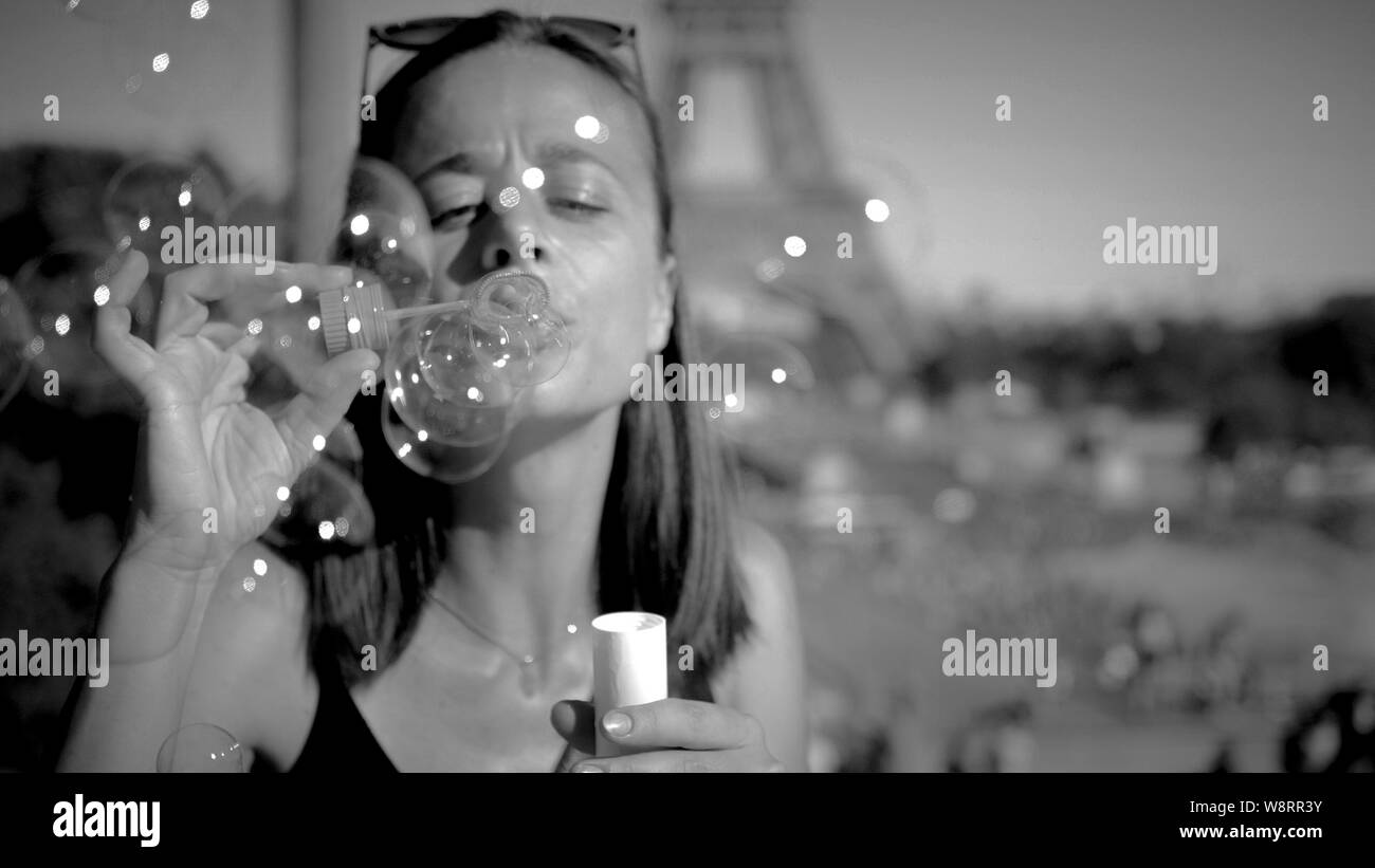 Giovane donna ha divertimento con insufflazione di bolle di sapone in Paris - Paris street photography Foto Stock