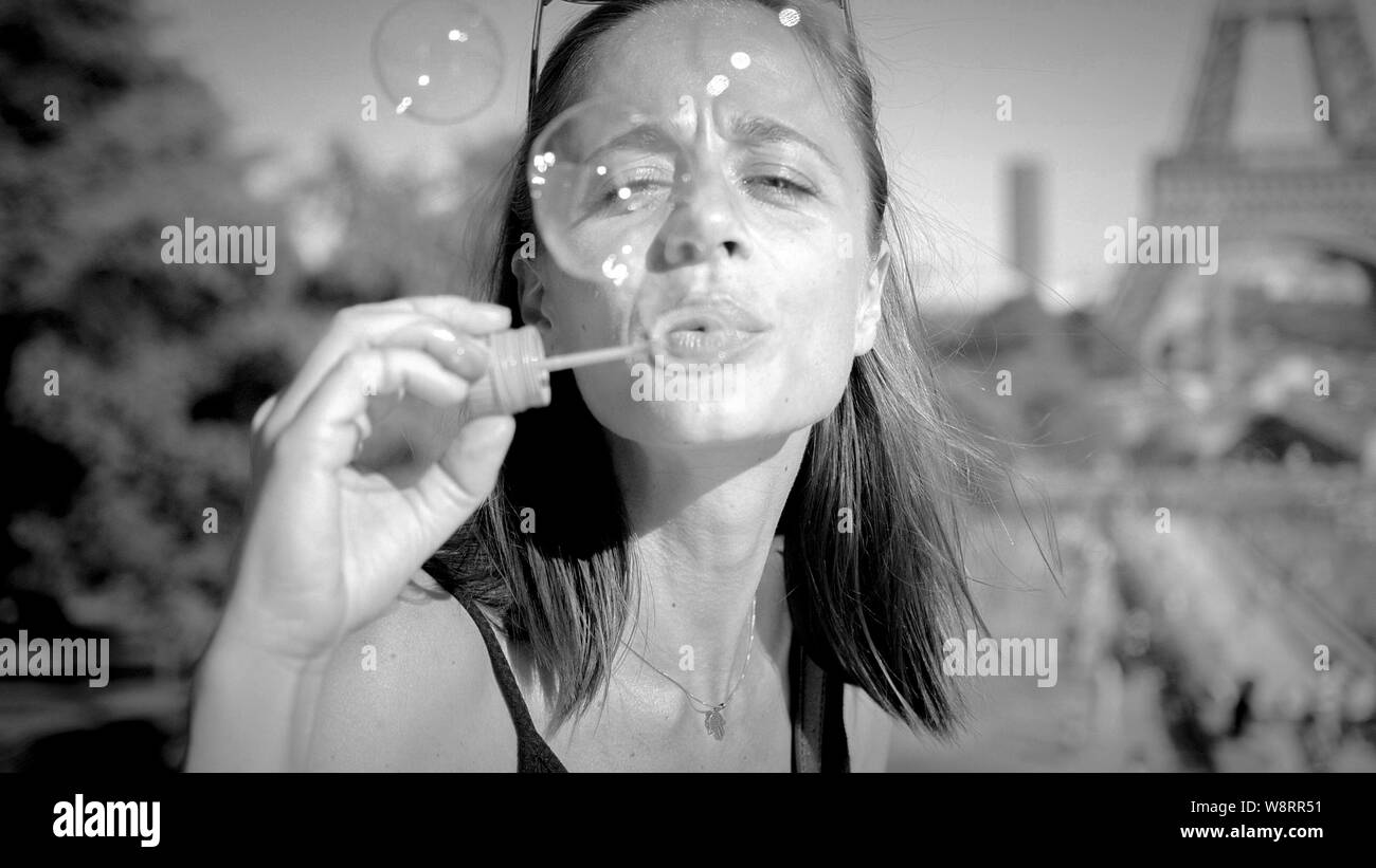 Giovane donna ha divertimento con insufflazione di bolle di sapone in Paris - Paris street photography Foto Stock