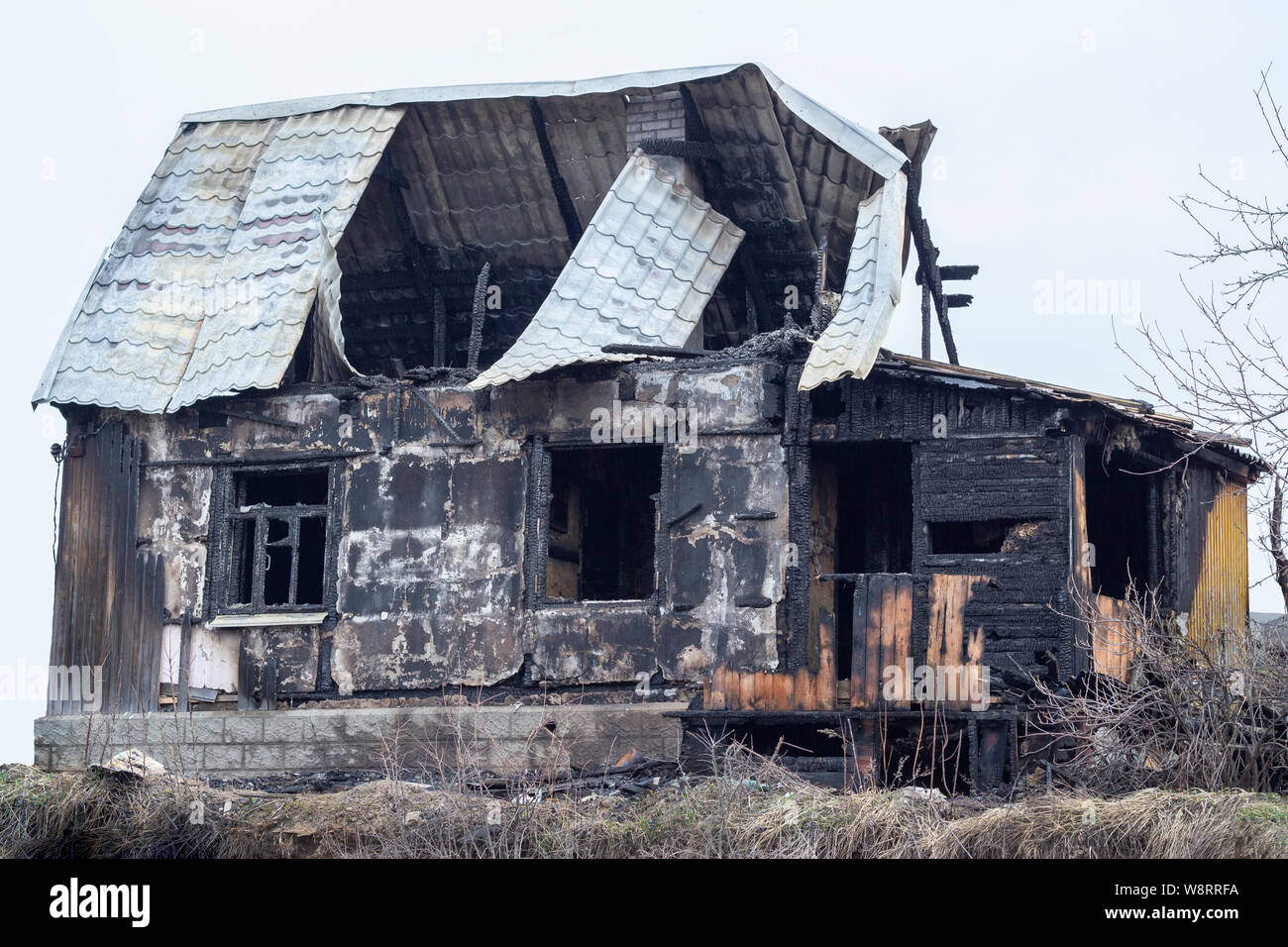 Bruciò legno casa, carbonizzati nero scheletro di una casa di campagna. Registri carbonizzati rimasti dalla casa di villaggio. Muri carbonizzati, finestre vuote e cava r Foto Stock