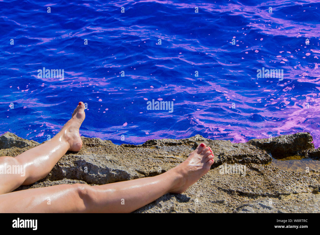 La donna per le gambe e il mare. Ragazza piedi prendere il sole sulla spiaggia in riva al mare. - Immagine Foto Stock