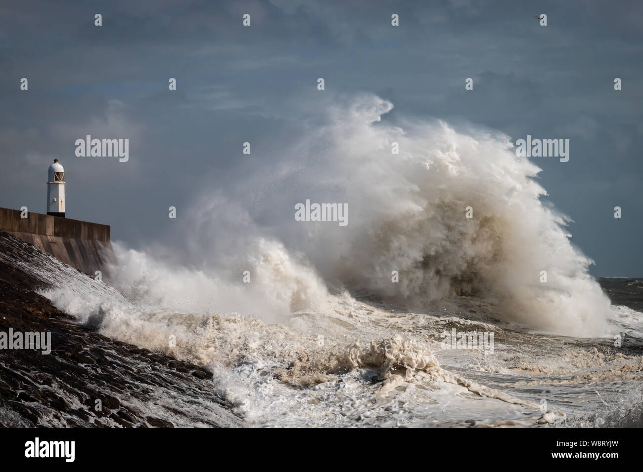 Enormi onde accanto a un faro su un giorno di tempesta (Porthcawl, Wales, Regno Unito) Foto Stock