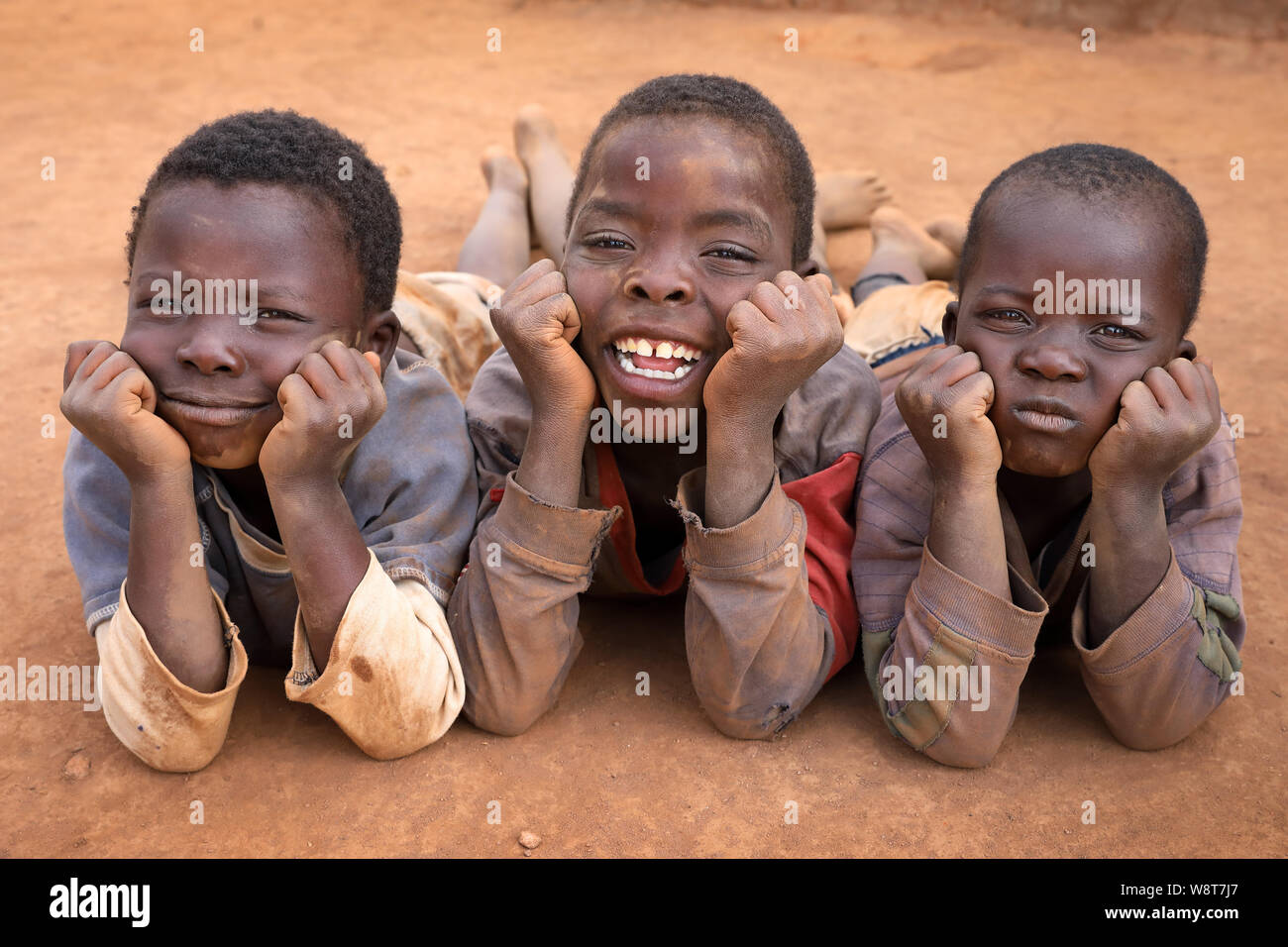 Ragazzi rilassatevi sulla terra in un remoto villaggio vicino Ntchisi. Il Malawi è uno dei paesi più poveri del mondo. Foto Stock