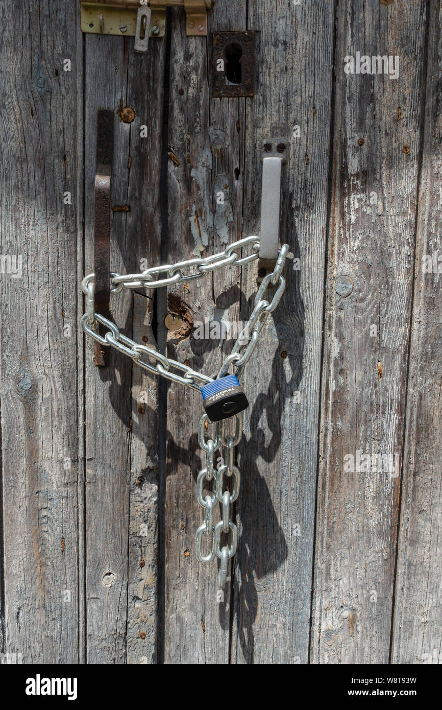 Primo piano il lucchetto e catena fissato sulla porta vecchia Foto Stock