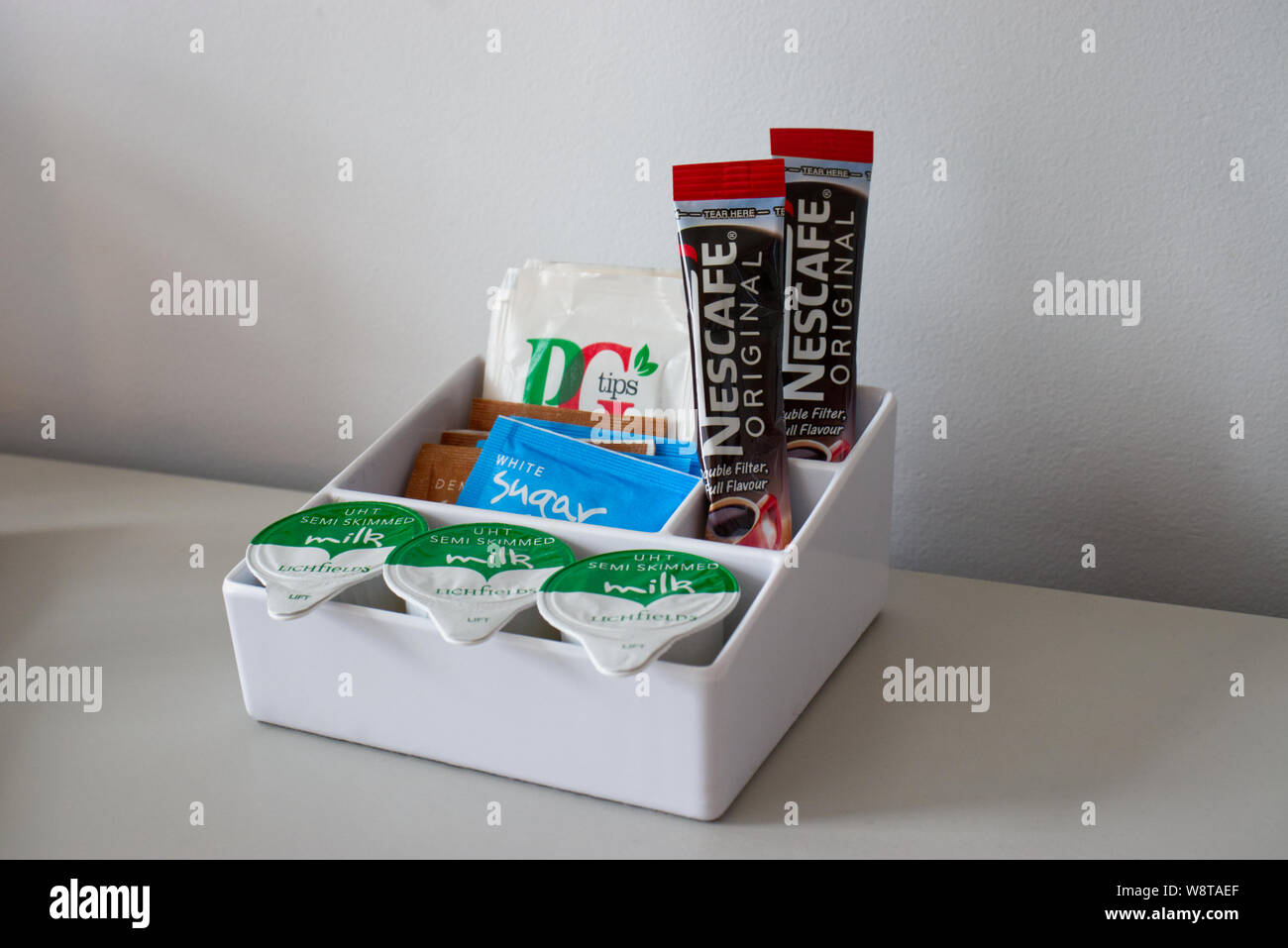 Singoli thè, caffè, latte e zucchero porzioni in un recipiente del tipo che si trovano tipicamente in camere di hotel Foto Stock