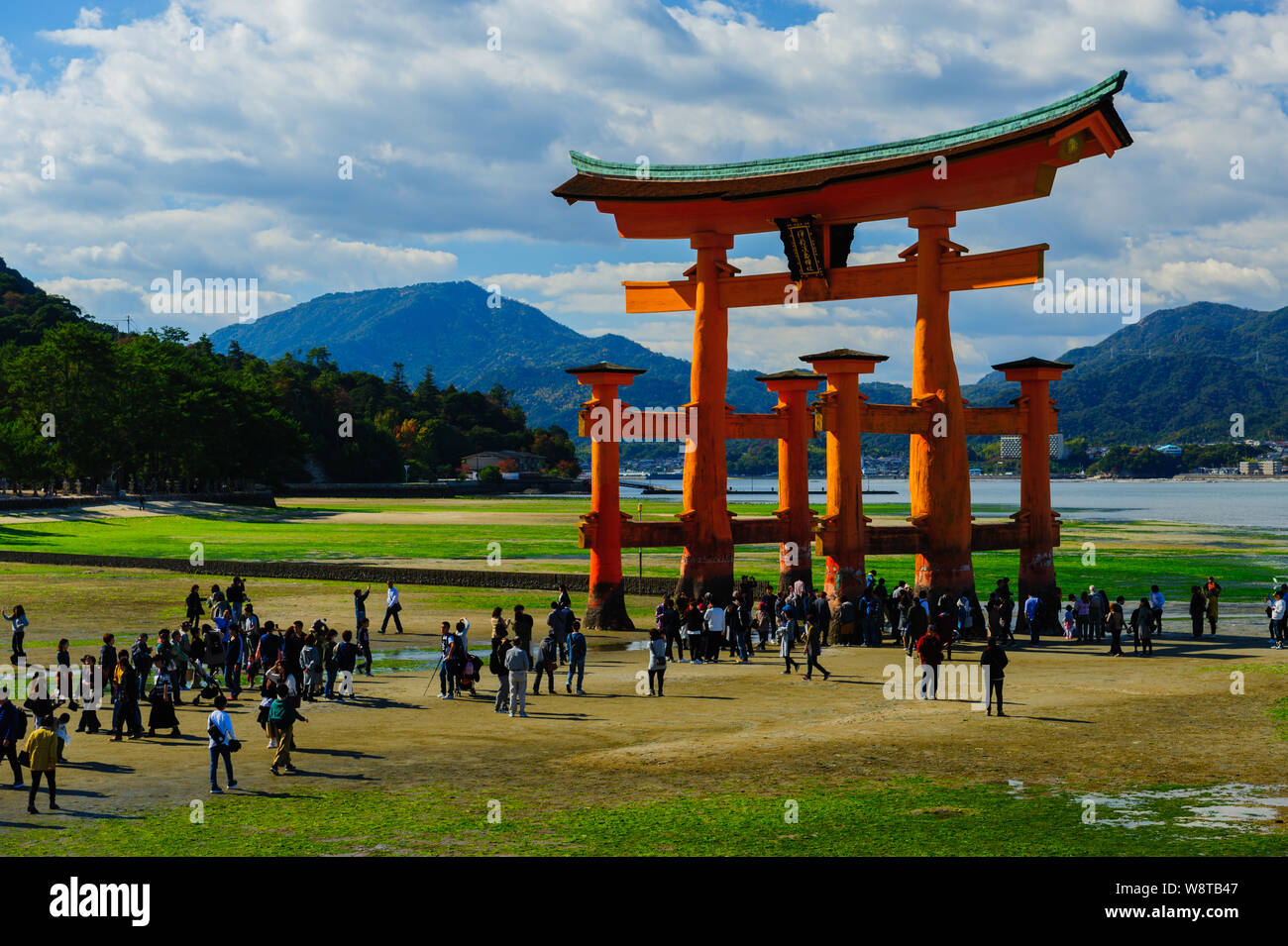 Gruppo di persone che circonda iconico vermiglio grande Torii su Miyajimas Sacrario di Itsukushima-jinja in acque basse condizioni, Giappone Novembre 2018 Foto Stock