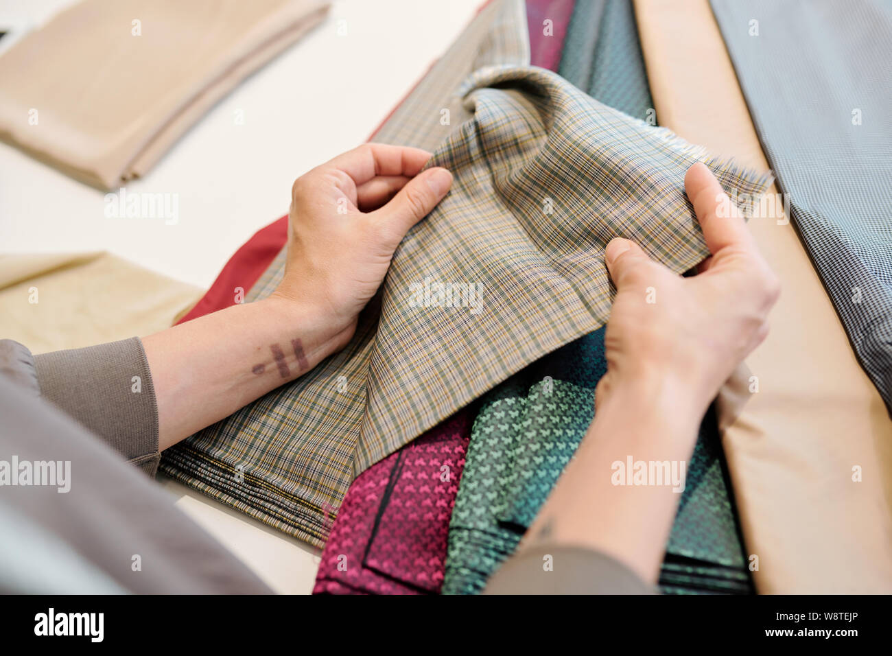 Le mani umane tenendo pezzo di tessuto mentre scegliendo un adatto Foto Stock