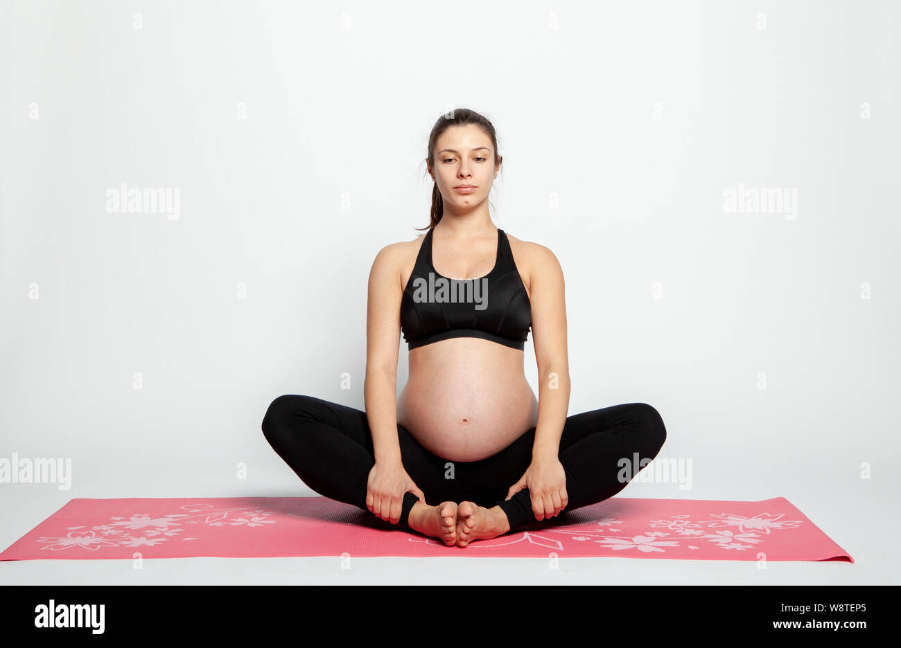 Giovane donna incinta facendo ginnastica con fitball e manubri. Foto Stock