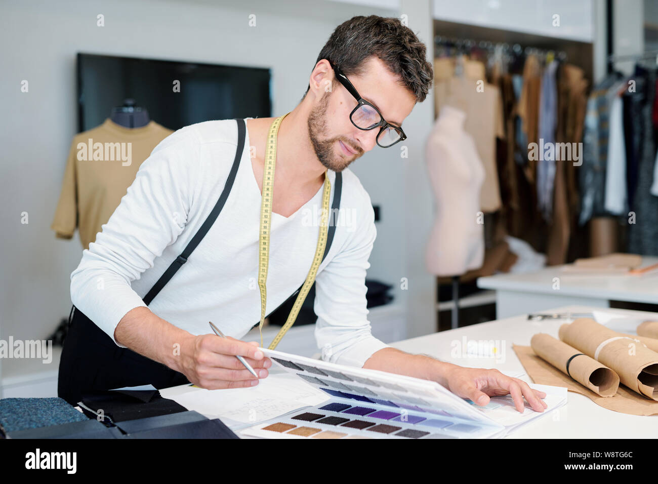 Maschi giovani designer di moda guardando i campioni tessili nel catalogo Foto Stock
