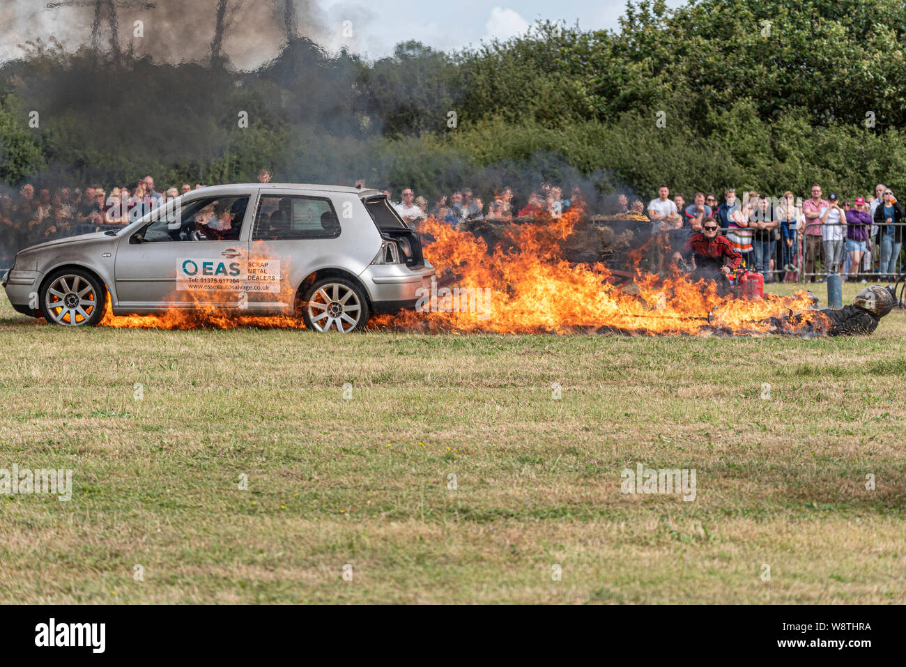Scott May's Daredevil Stunt Show a Rayleigh, Essex, Regno Unito. Un'auto che trascina uno stuntman attraverso il fuoco. Fiamme Foto Stock