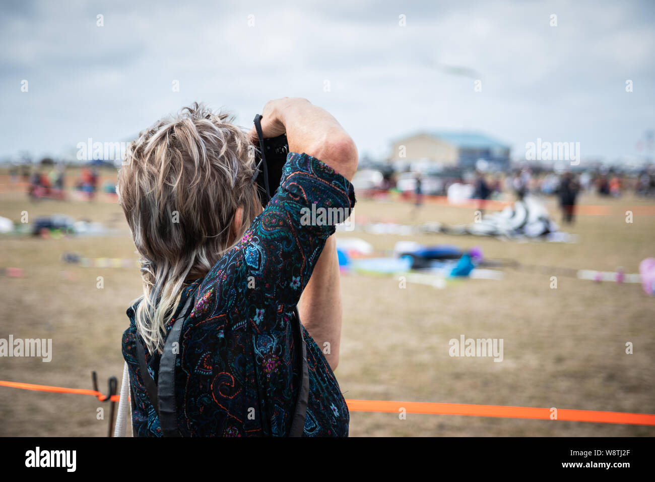 Una femmina di fotografo a scattare foto con una fotocamera ad un evento esterno Foto Stock