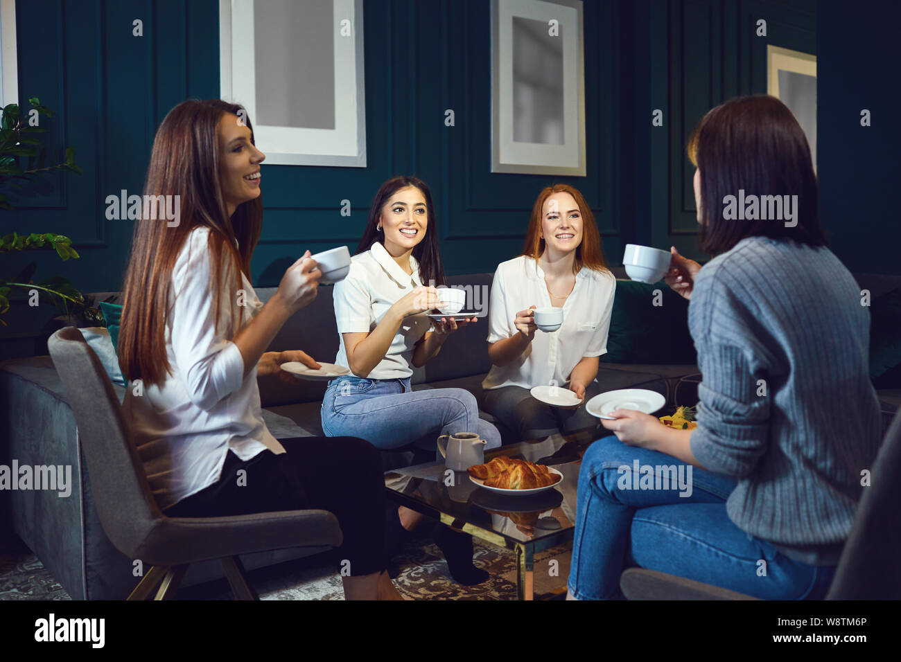 Le donne bere il caffè di ridere in occasione di una riunione di amici a casa. Foto Stock