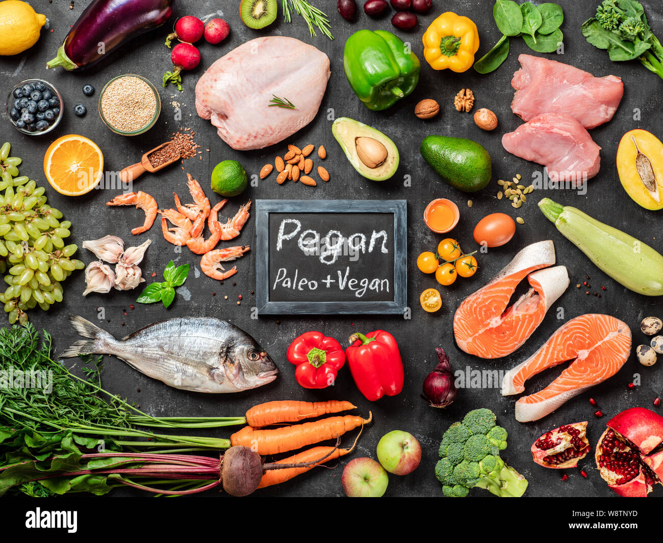 Dieta Pegan conept. Vegan plus paleo dieta ingredienti alimentari - Verdura, frutta, carne cruda e pesce su sfondo scuro. Vista superiore o laici piatta Foto Stock