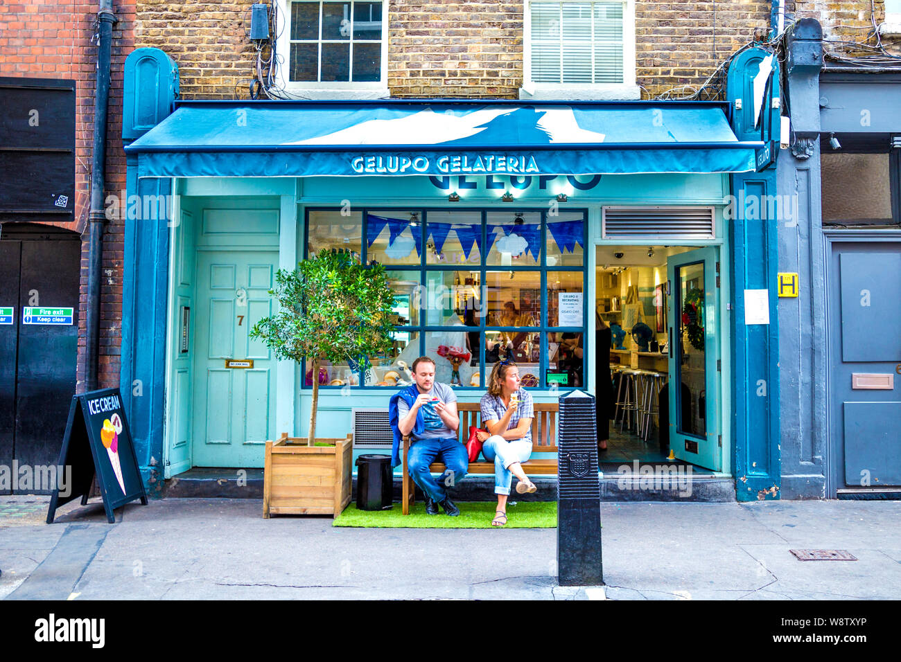 Due persone a mangiare il gelato di fronte Gelupo Gelateria, Soho, London, Regno Unito Foto Stock