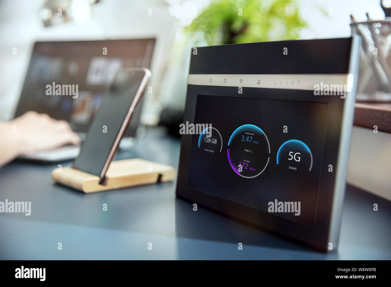 Moderno 5G router wi-fi con display sul banco e dispositivi in background. Interfaccia su schermo è stato creato nel programma di grafica. Foto Stock