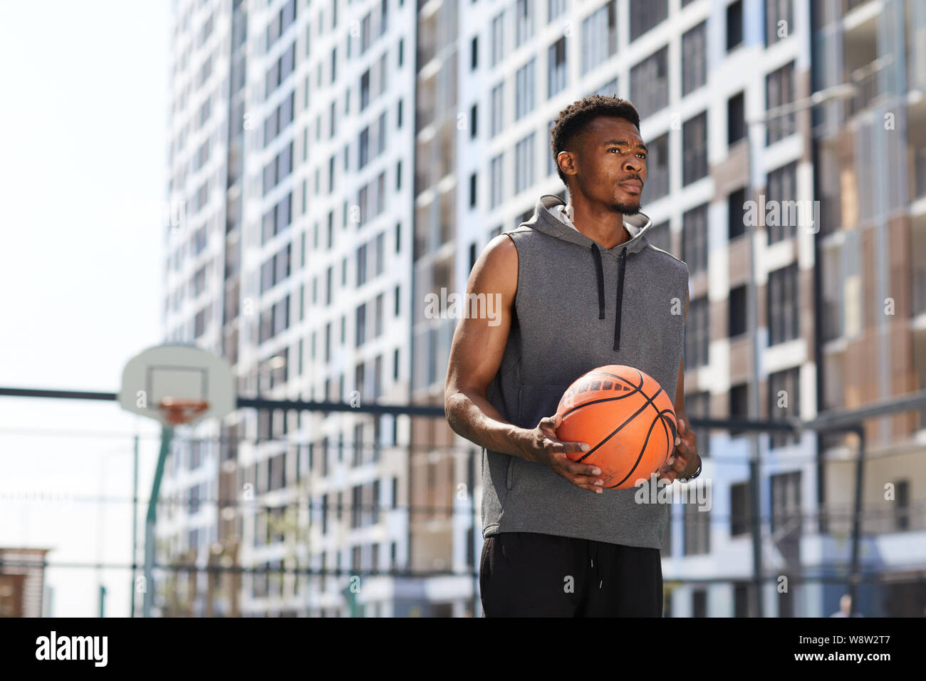 Vita ritratto di maschile uomo africano holding basket ball in corte all'aperto, spazio di copia Foto Stock