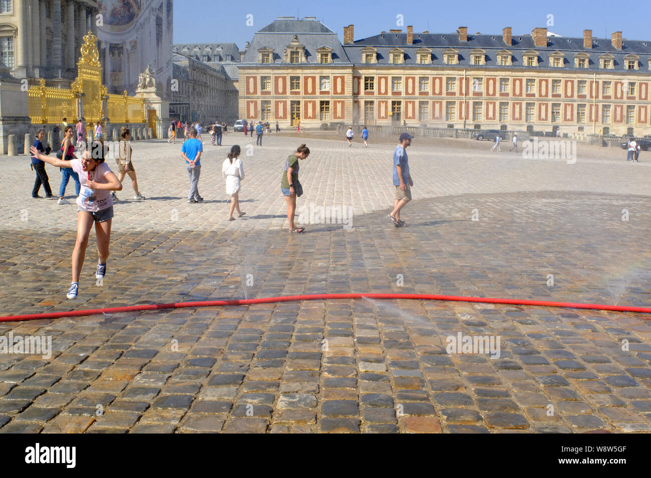 Persone il raffreddamento di fronte il Palazzo di Versailles a Parigi in Francia in una giornata molto calda Foto Stock