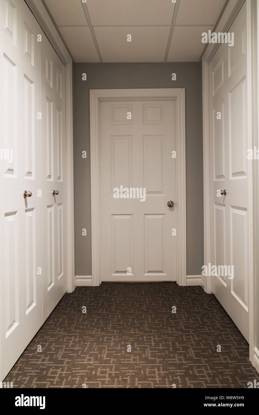 Corridoio con sfumature di marrone tappeti da muro a muro bianco e porte armadio all'interno di una casa residenziale Foto Stock