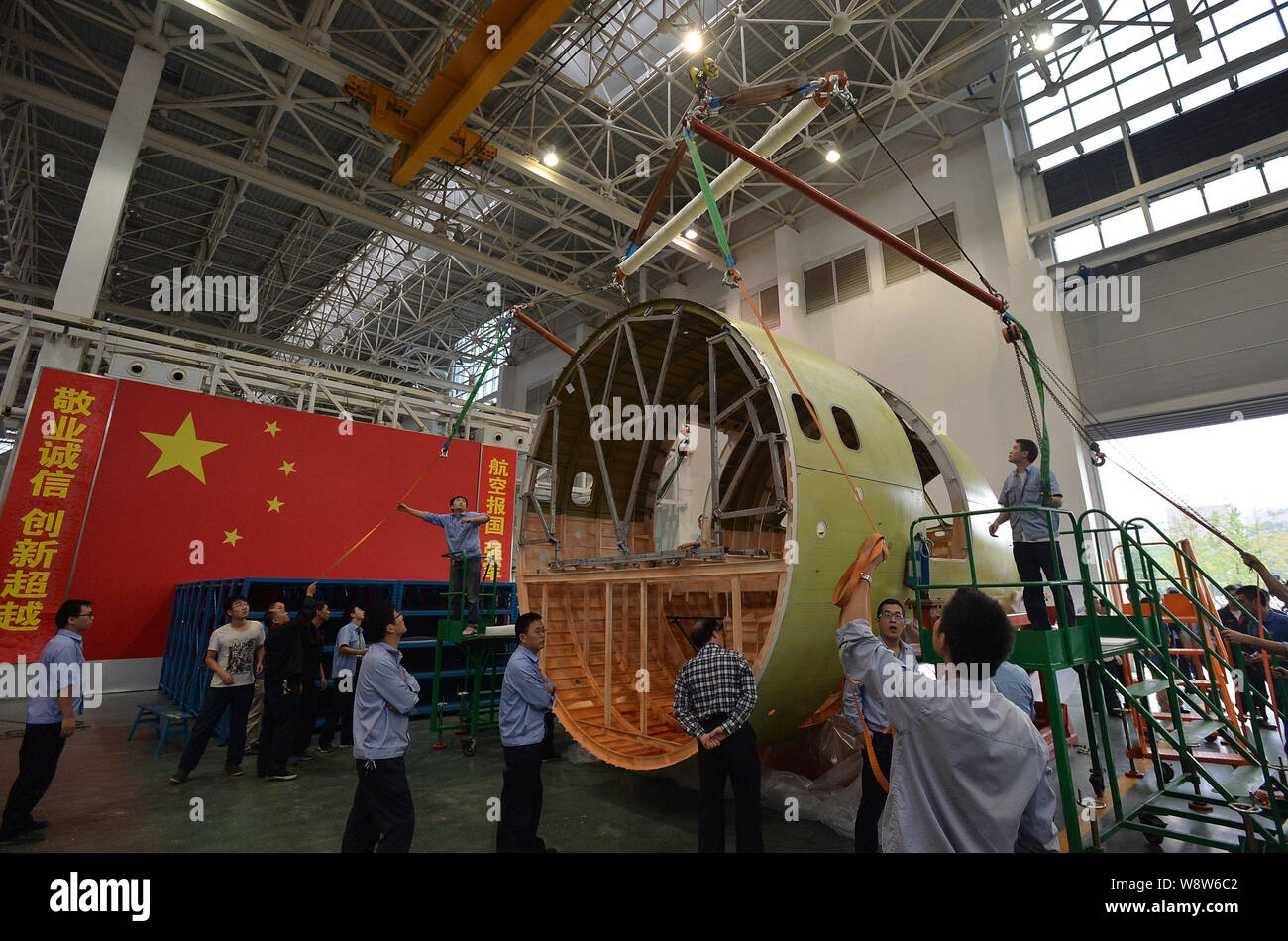 Ingegneri cinesi e tecnici direttamente una gru per spostare il naso della Cina il primo la produzione nazionale di fatto jet del passeggero aereo C919 presso lo stabilimento di Chengdu Foto Stock