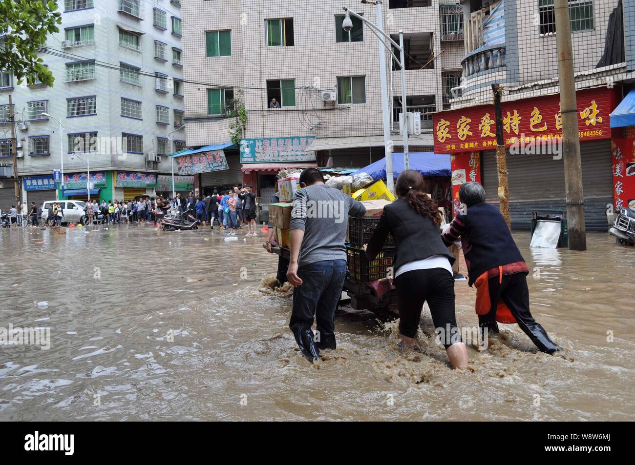 Locali residenti cinesi spingere un triciclo a superficie piana su una strada allagata dalla pioggia in Tongzi county, Zunyi city, southwest Chinas Guizhou, 3 Giu Foto Stock