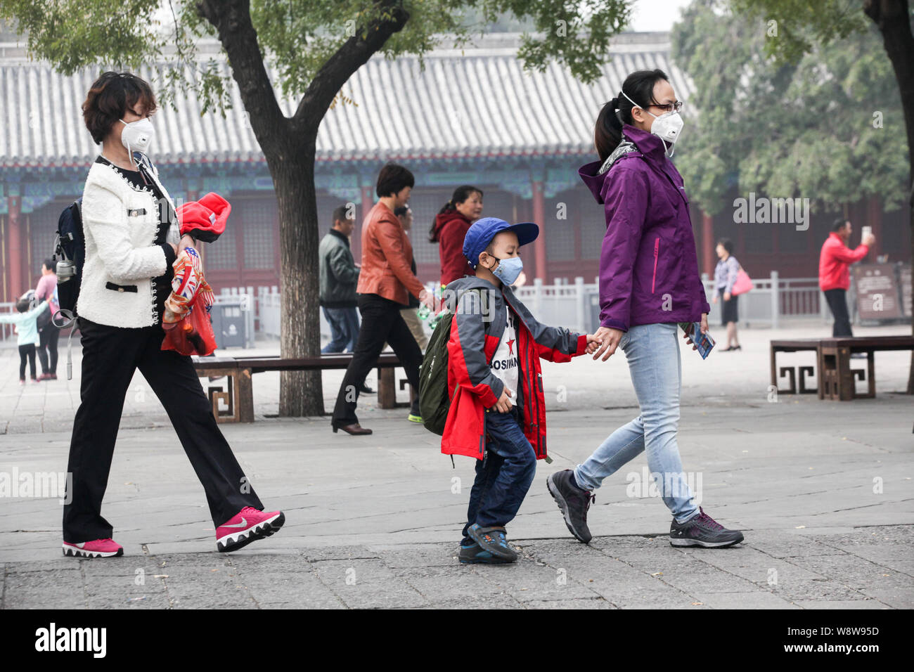 I turisti che indossano maschere viso visita un attrazione in pesanti smog a Pechino in Cina, 20 ottobre 2014. Le prospettive per gli operatori turistici in Medio unito Foto Stock