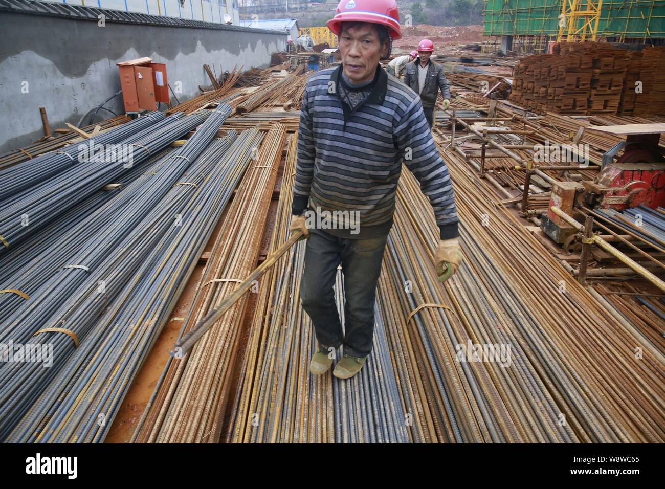--FILE--cinese dei lavoratori migranti che portano in acciaio di rinforzo bar presso il cantiere per la costruzione di un immobile commerciale progetto nella città di Jiujiang, est Chinas J Foto Stock