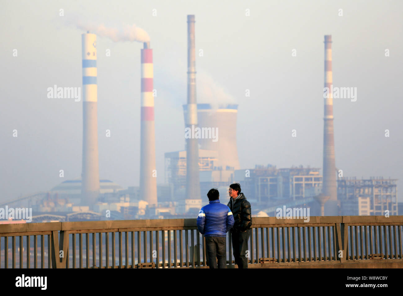 --FILE--due uomini parlare su un ponte in prossimità di un impianto alimentato a carbone nella città di Jiujiang, Cina orientale della provincia di Jiangxi, 23 gennaio 2014. Un progetto riveduto di Foto Stock