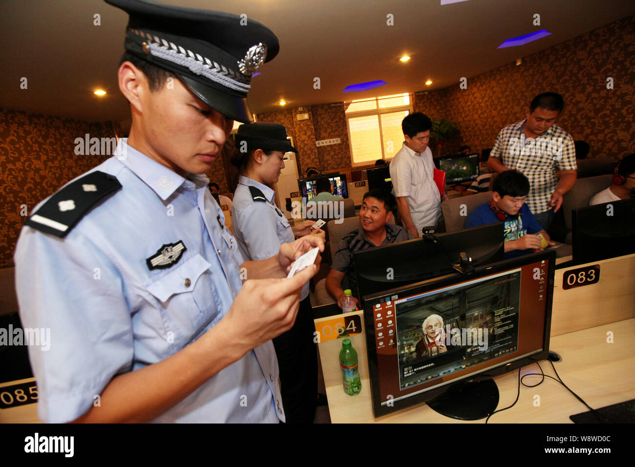 --FILE--La polizia cinese e funzionari di polizia verificare le carte di identità dei giovani netizens riproduzione di giochi online o guardare i video online in un Internet café Foto Stock