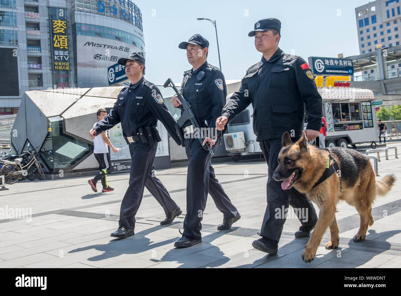 Poliziotti cinesi armati di pistole pattugliare una strada con un cane di polizia a Pechino, in Cina, il 12 maggio 2014. La polizia di Pechino distribuito 150 pattuglia armata v Foto Stock