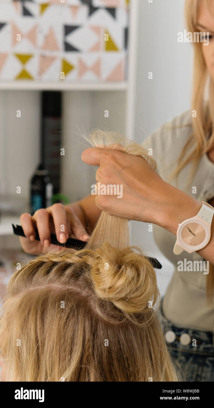 Hairtician costruisce bun superiore. Acconciatura sul bob. Servizi di parrucchiere. Creazione di sera Acconciature eleganti alla moda donna acconciature. Processo di h Foto Stock