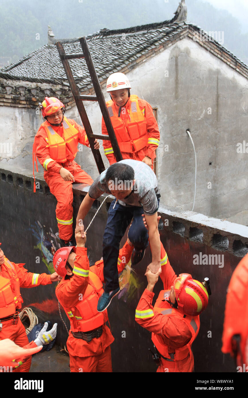 I soccorritori di aiutare un uomo intrappolato lasciare una casa sommersa causati dalla pioggia nella contea di Fenghuang, porcellane centrale nella provincia del Hunan, 15 luglio 2014. Circa 720 Foto Stock