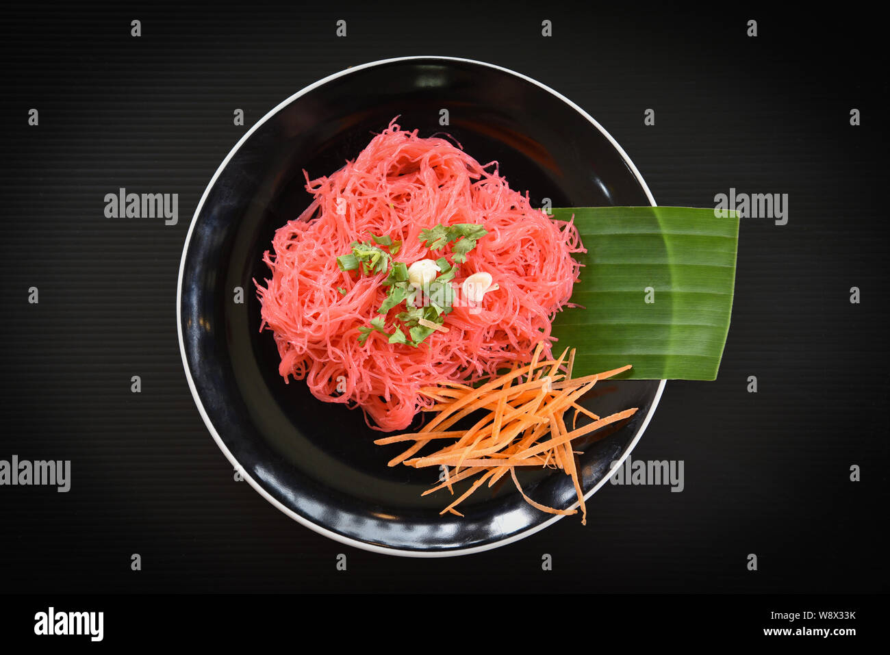 Vermicelli di riso rosa e frittura / di verdure saltate in padella il riso tagliatelle  con salsa rossa servita su piastra su sfondo nero , Thailandese in stile  asiatico tagliatelle Foto stock - Alamy