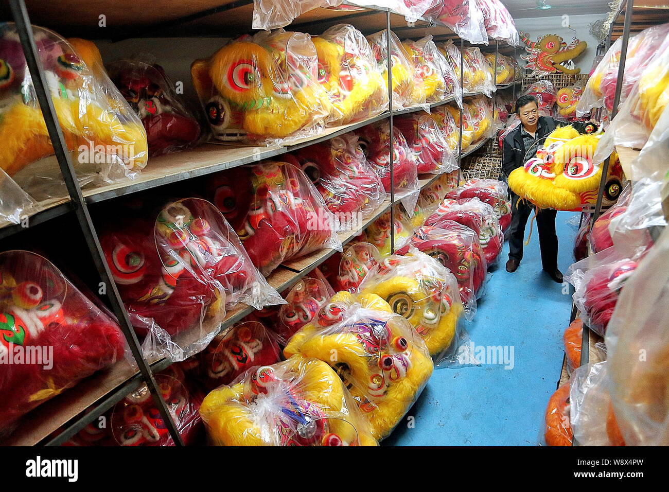 Un lavoratore cinese di scorte ballare i Lions nel magazzino di una fabbrica nella città di Guangzhou, Cina del sud della provincia di Guangdong, 3 dicembre 2014. Lion da Foto Stock