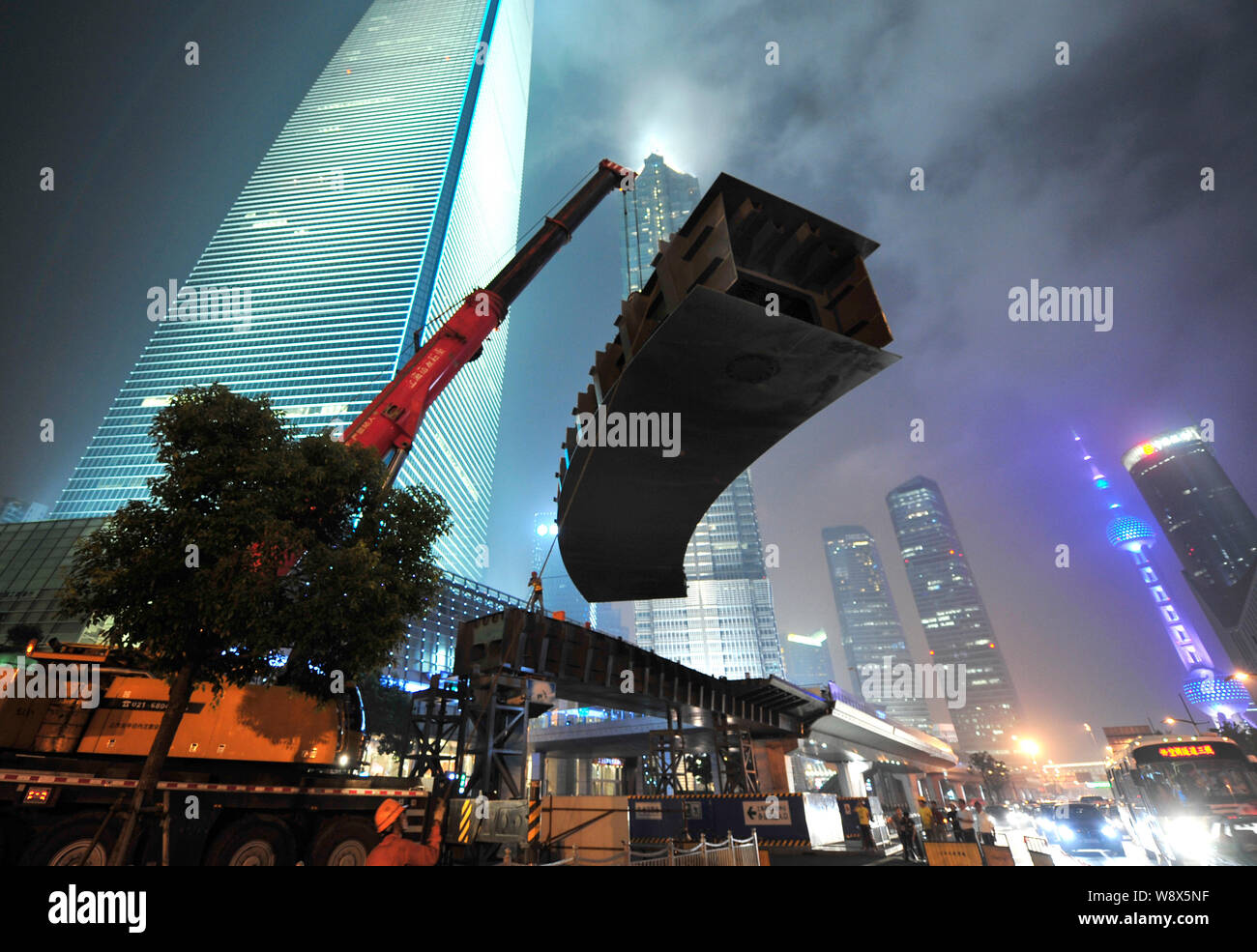Una gru solleva una 40-tonnellata trave in acciaio in posizione per la costruzione di una passerella aerea di Pudong di Shanghai, Cina, 2 settembre 2014. Un skywalk collegherà l Foto Stock