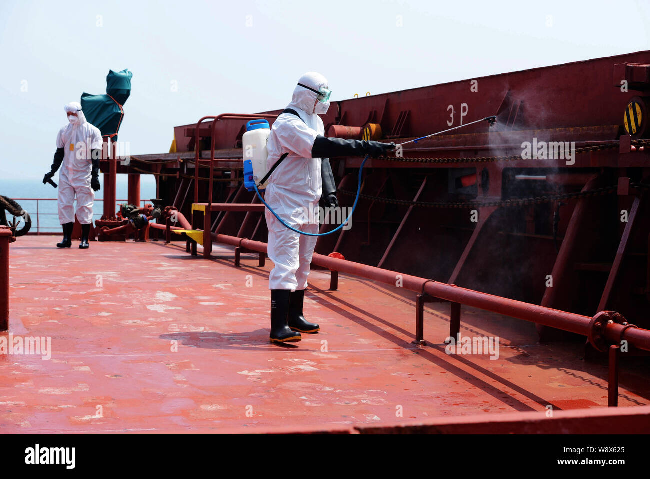 Quarantena cinese lavoratori indossare abbigliamento protettivo Disinfettare il ponte della nave che trasporta merci alla rinfusa alfa amicizia il trasporto di minerali da Ebola-colpite Sier Foto Stock