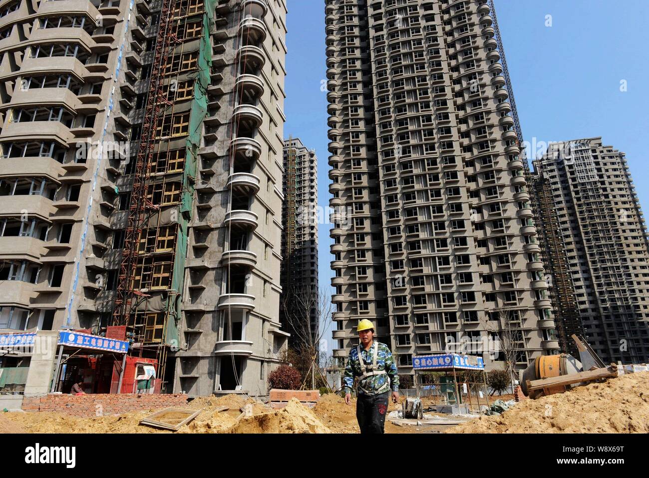 --FILE--un cinese lavoratore migrante passeggiate passato ad alta edifici di appartamenti presso il cantiere per la costruzione di un progetto residenziale a Qingdao City East mento Foto Stock