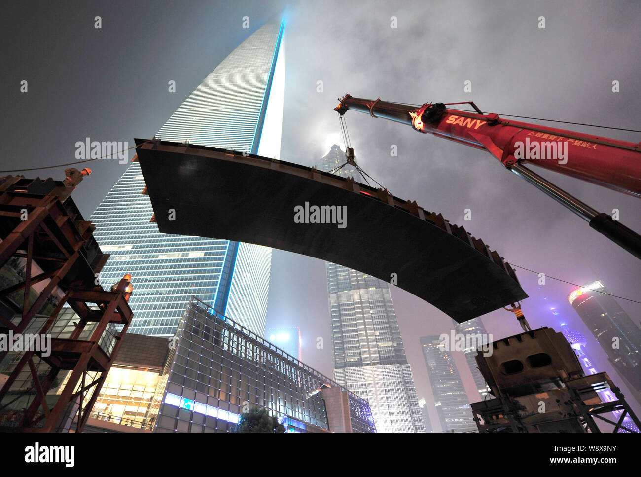 Una gru solleva una 40-tonnellata trave in acciaio in posizione per la costruzione di una passerella aerea di Pudong di Shanghai, Cina, 2 settembre 2014. Un skywalk collegherà l Foto Stock