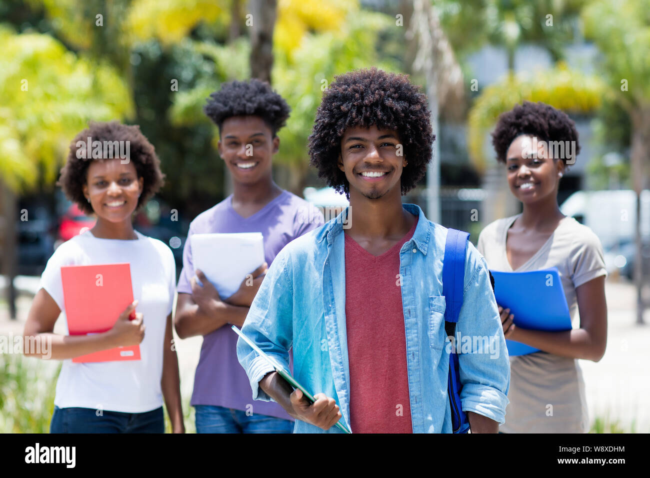 African American studente universitario con gruppo di African American studenti all'aperto in estate Foto Stock