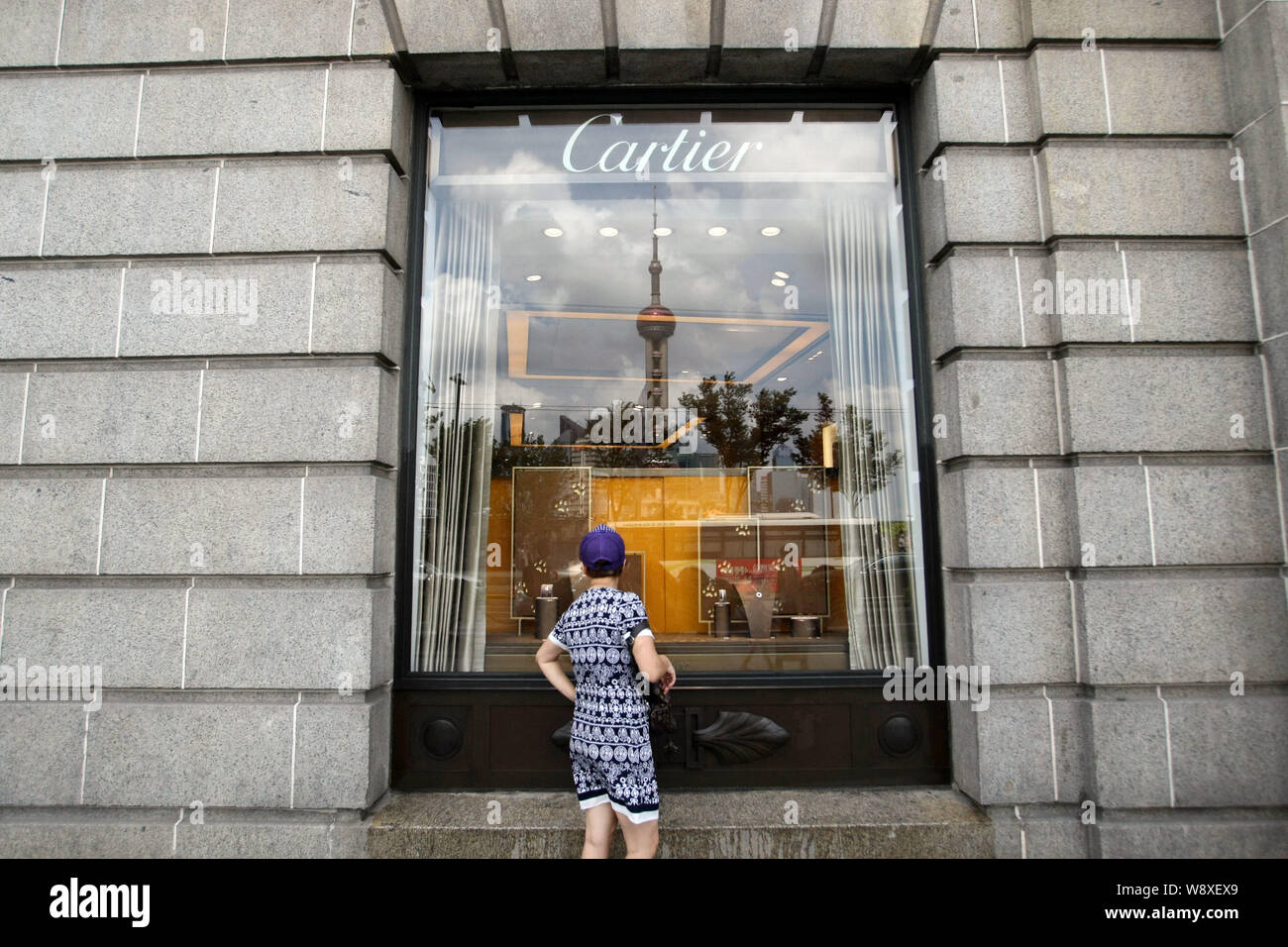 Un pedone guarda nella boutique di moda di Cartier al Bund 18 in Cina a Shanghai, 7 agosto 2014. Lungo il Bund e la famosa area del litorale di Foto Stock