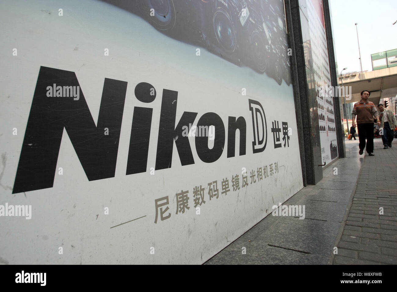 I pedoni a piedi passato un annuncio per fotocamere digitali Nikon in Cina a Shanghai, 17 marzo 2014. Chinas potente governo-controllata la televisione Foto Stock