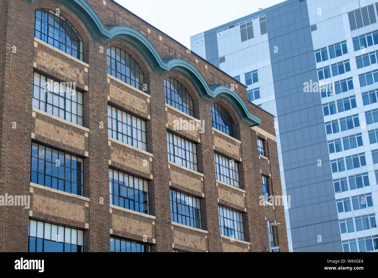 Un edificio in mattoni risalente agli inizi del XX secolo si erge in contast con un concetto moderno hotel situato in un quartiere storico che non smette di crescere. Foto Stock
