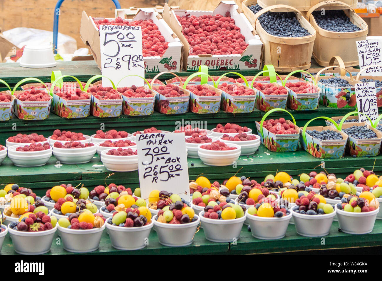 Cestini di frutta, soprattutto bacche, sono in vendita in un mercato agricolo su una strada soleggiata in estate. Foto Stock