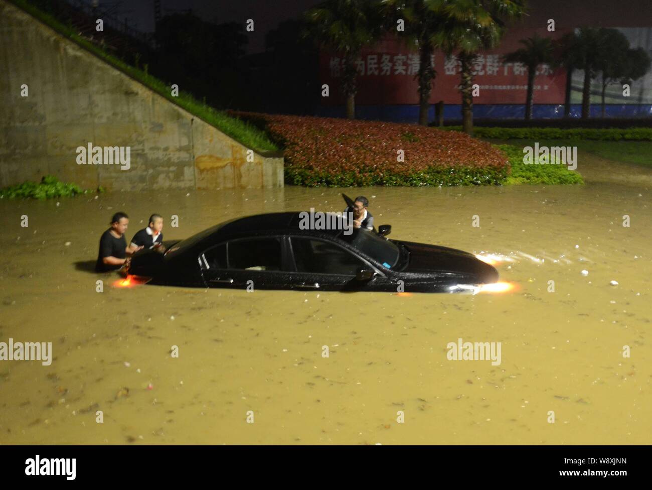 I residenti locali spingere le loro auto in un invaso street causato da un pesante acquazzone in lo sviluppo economico e tecnologico in zona Città Jiujiang, ea Foto Stock