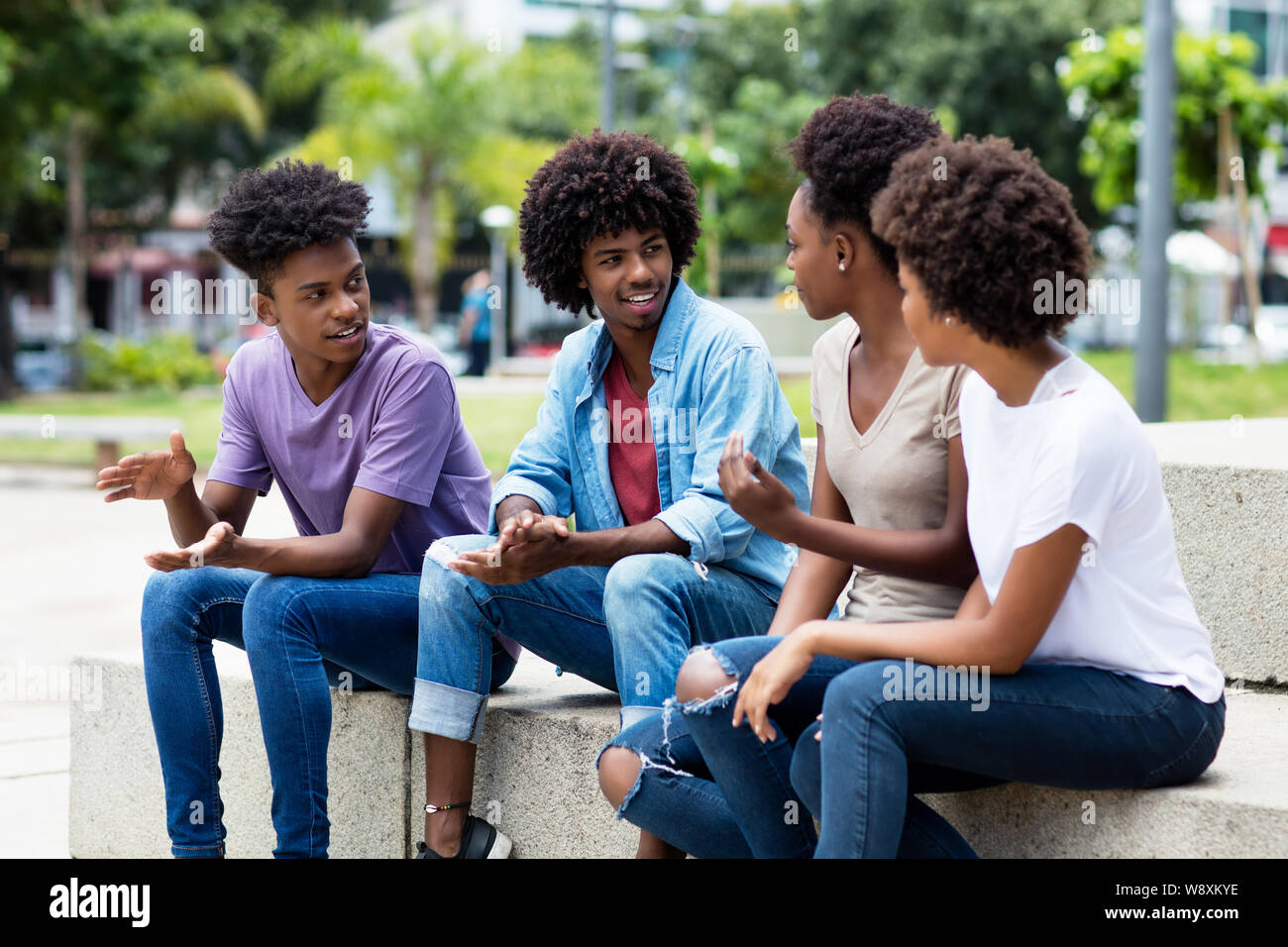 Gruppo di afro-americano di giovani adulti in discussione all'aperto in estate in città Foto Stock