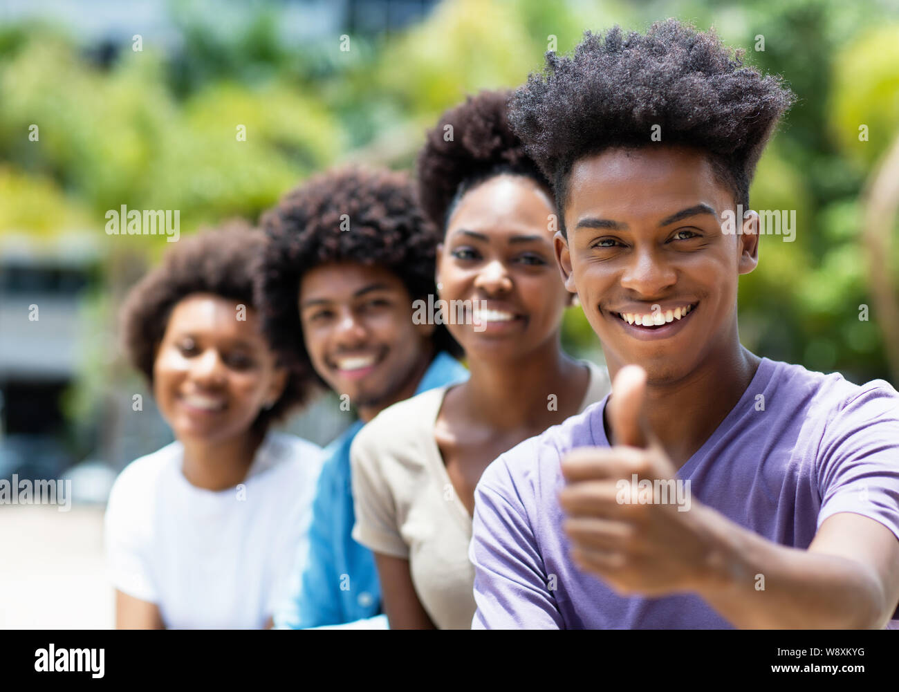 African American giovane uomo adulto con amici che mostra il pollice fino all'aperto in città in estate Foto Stock
