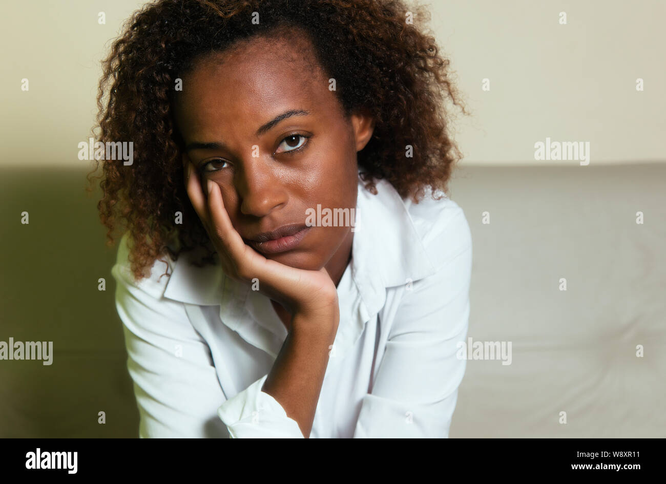 Triste americano africano donna con depressione guardando la telecamera indoor a casa Foto Stock