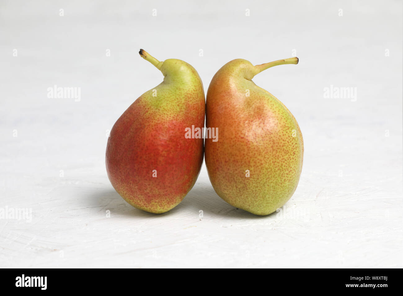 Brutto verdura , due pere mature di forma bizzarra ,sono inclinati . su uno sfondo bianco . i frutti sono come i pinguini . Foto Stock
