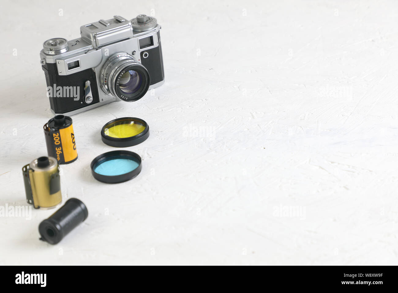 Vecchia pellicola vintage fotocamera bianco su sfondo a trama . due foto filtri blu e giallo e film in cassette. copia spazio. Foto Stock