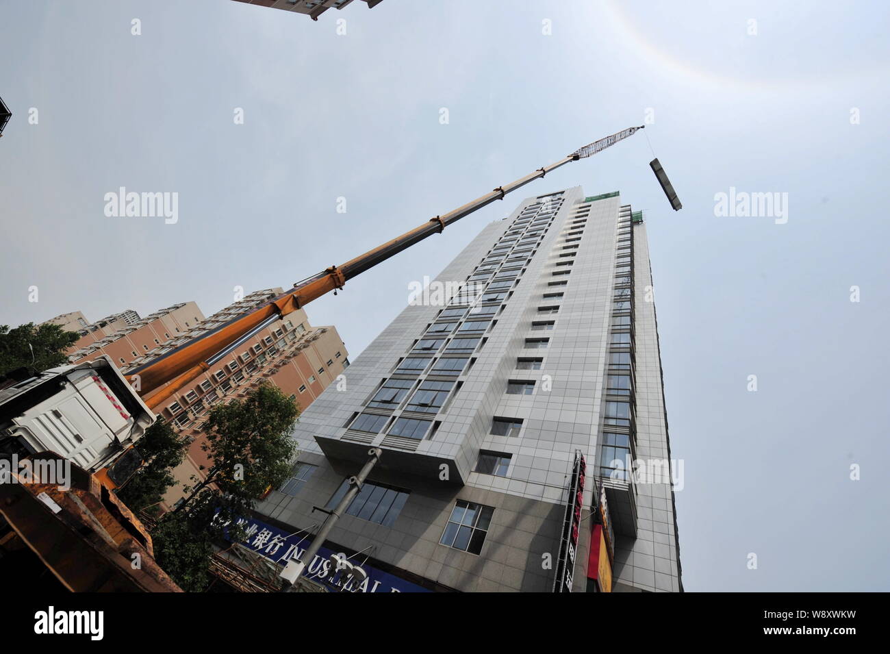 Un 260-ton heavy-duty gru viene utilizzata per demolire un illegalmente-costruzione sul tetto di un alto edificio di uffici a Pechino in Cina, 24 giu Foto Stock